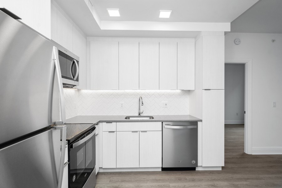 a white kitchen with stainless steel appliances and white cabinets