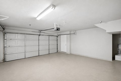 A spacious garage with a closed white door and a white ceiling.