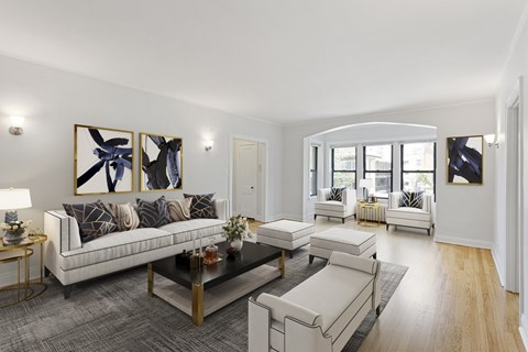 A modern living room with a white sofa, a coffee table, and a painting on the wall.