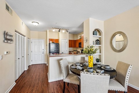 A dining room with a table set for two and a television in the background.