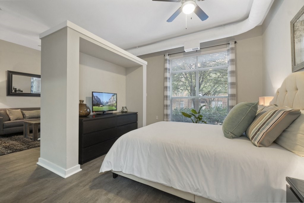 Bedroom with wood style flooring, large window, and ceiling fan