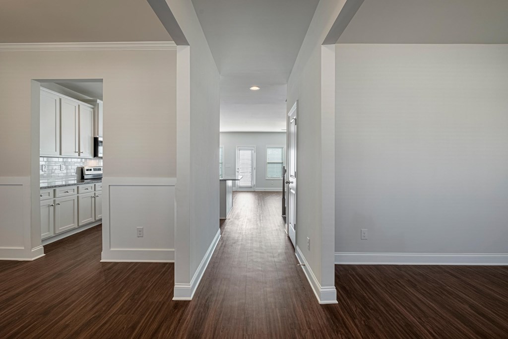 a living room and hallway with white walls and wood floors