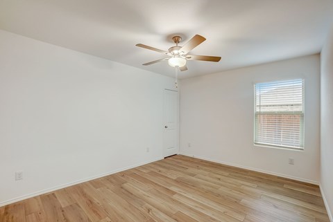an empty living room with hardwood floors and a ceiling fan