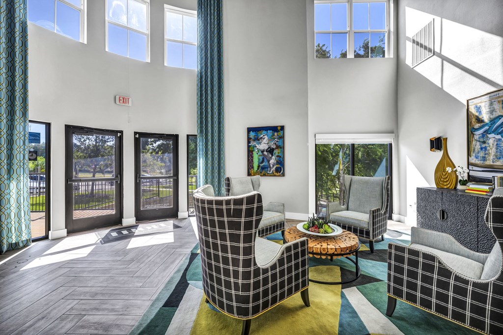 a living room with couches and chairs and large windows