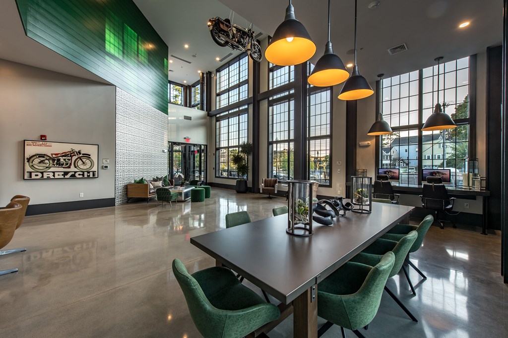 A conference room with a long table and green chairs.