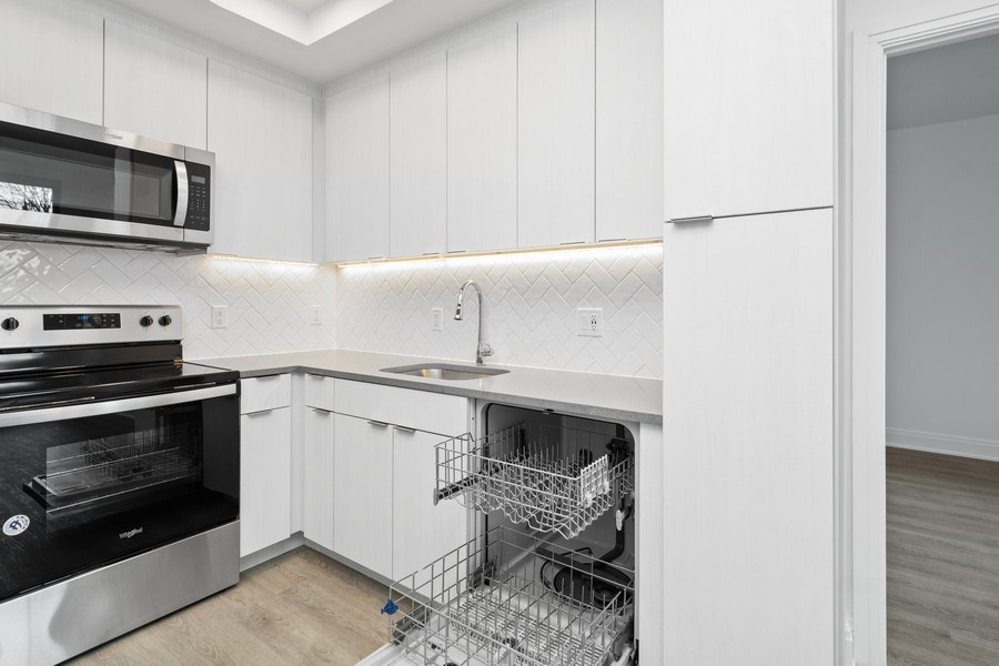a kitchen with white cabinets and a dishwasher and a sink