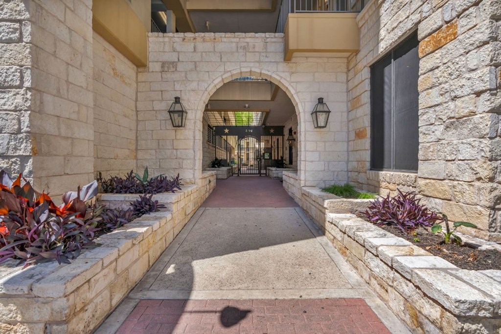 the entrance to a building with stone walls and a walkway with plants