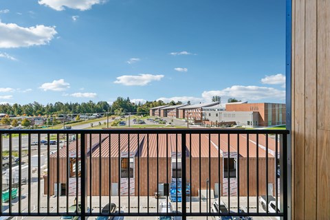 A view from a balcony overlooking a parking lot and buildings.