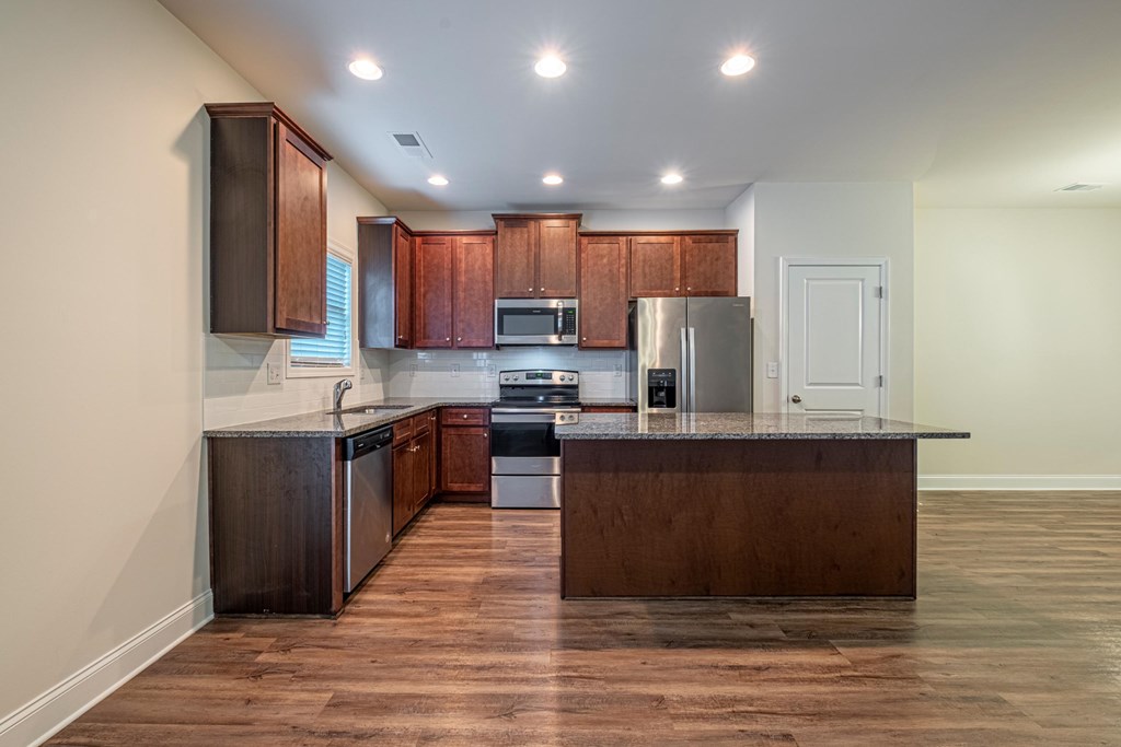 an empty kitchen with wooden cabinets and stainless steel appliances