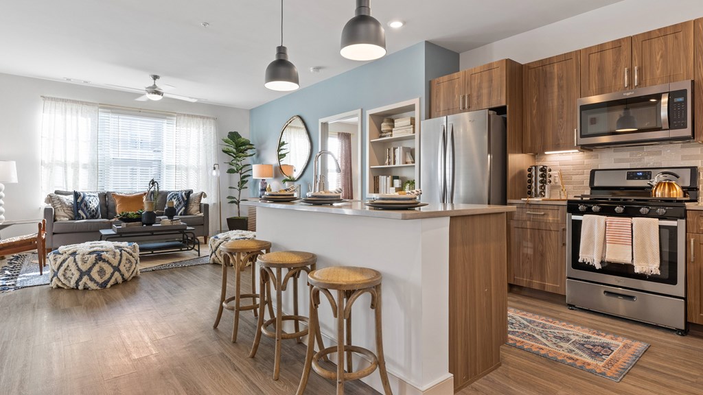 Open kitchen with island, stainless steel appliances, wood grain cabinets and tile backsplash