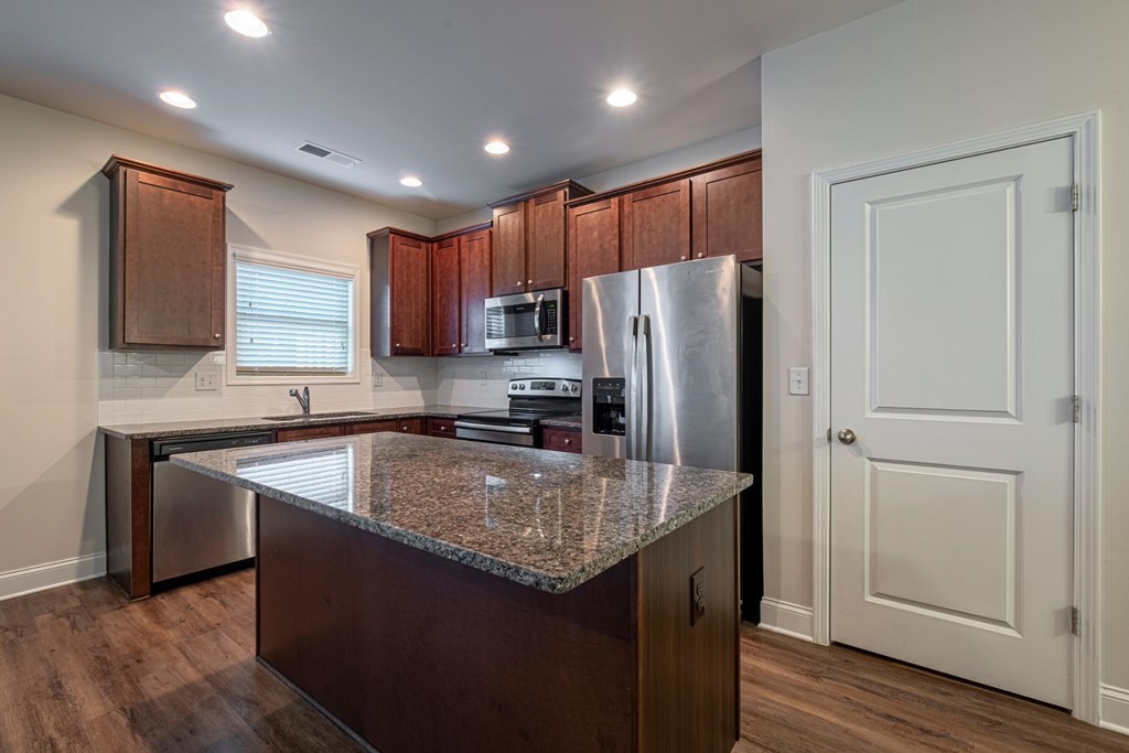 a kitchen with a granite counter top and a stainless steel refrigerator