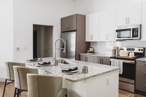 A kitchen with a marble countertop and stainless steel appliances.