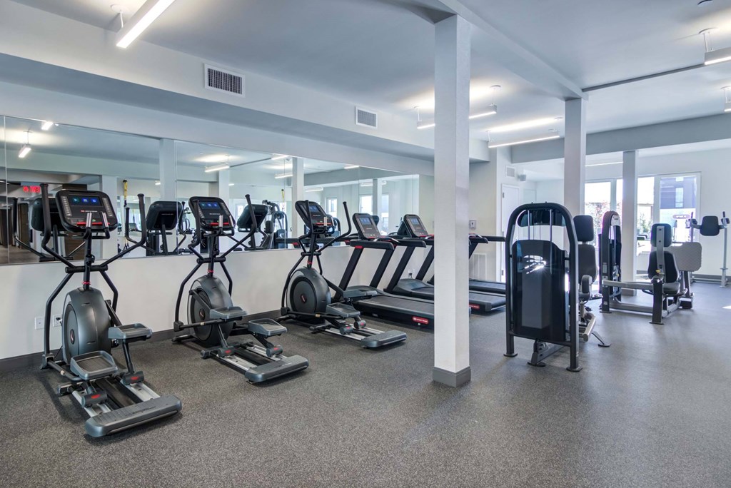 The Beacon fitness center with cardio and weight machines, yoga balls, and a mirror wall