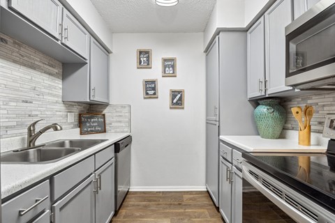 A kitchen with grey cabinets and a white counter top.