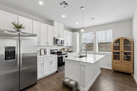 A modern kitchen with a stainless steel refrigerator and white cabinets.