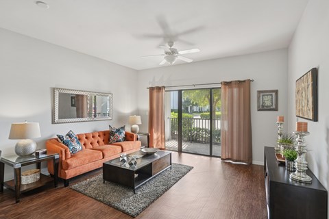 A living room with a brown sofa, a coffee table, and a ceiling fan.