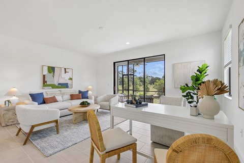 A well-lit, modern living room with a white sofa set, a wooden chair, and a dining table with chairs.