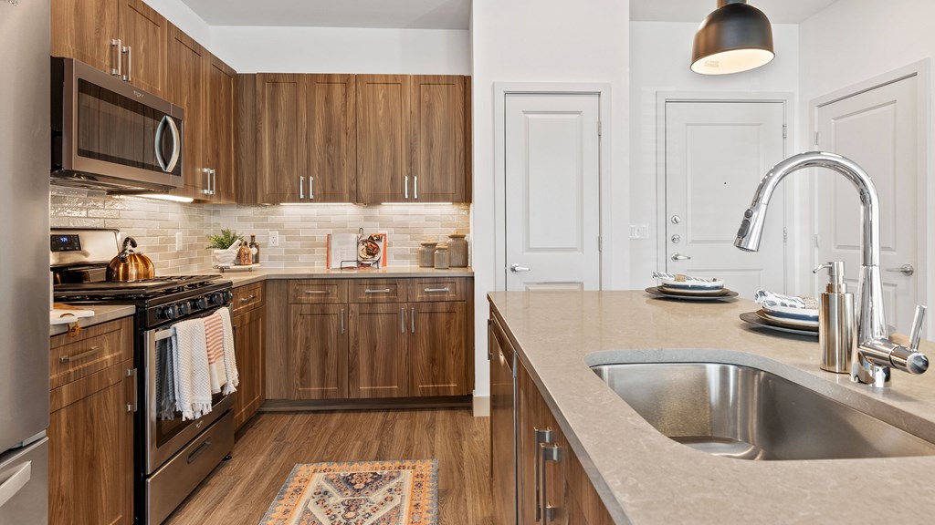 Kitchen with island, stainless steel appliances, wood grain cabinets and tile backsplash