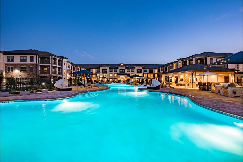 a large swimming pool in front of a hotel at night