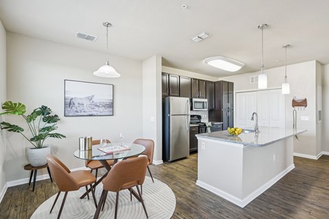 A kitchen with a table and chairs in the foreground and a refrigerator in the background.