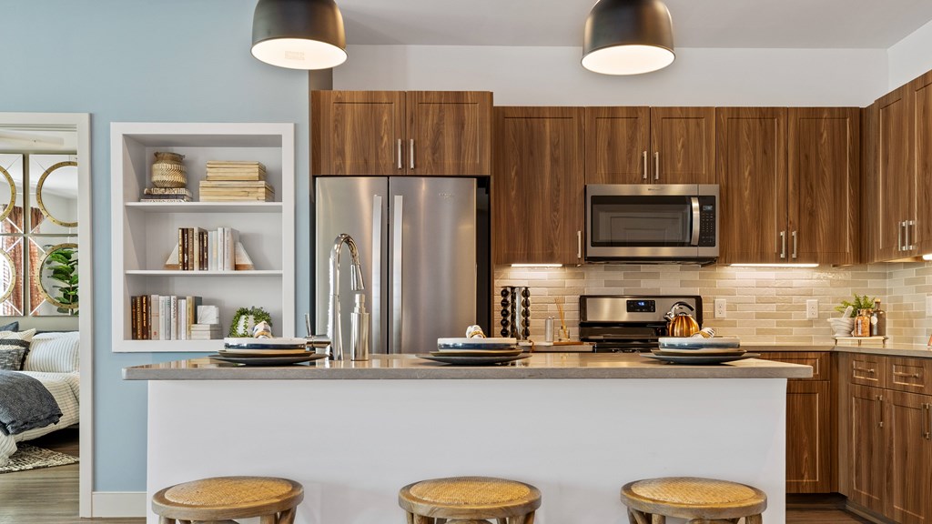 Kitchen with island, stainless steel appliances, wood grain cabinets and tile backsplash