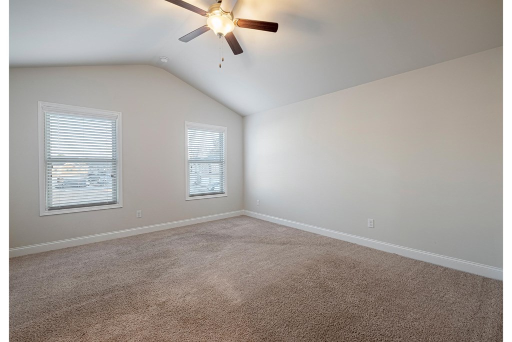 an empty room with a ceiling fan and two windows