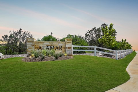 a sign that says in front of a green lawn and a fence