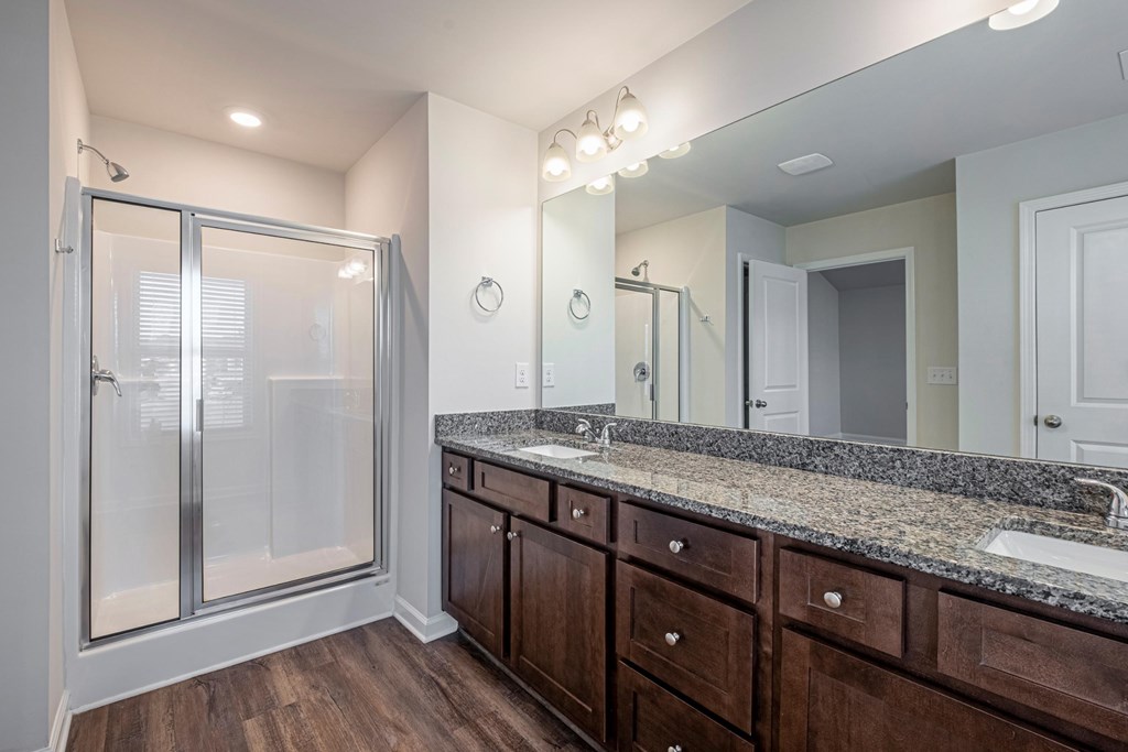 a bathroom with a large shower and granite counter tops and wooden cabinets