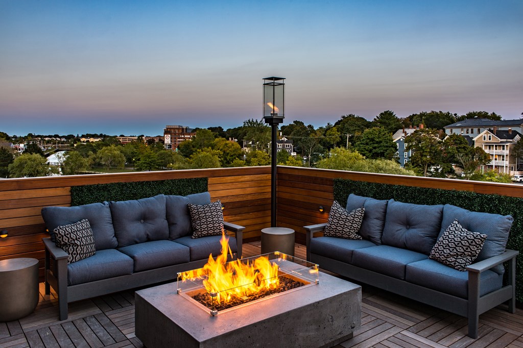 A fire pit sits in the middle of a patio with two couches on either side.
