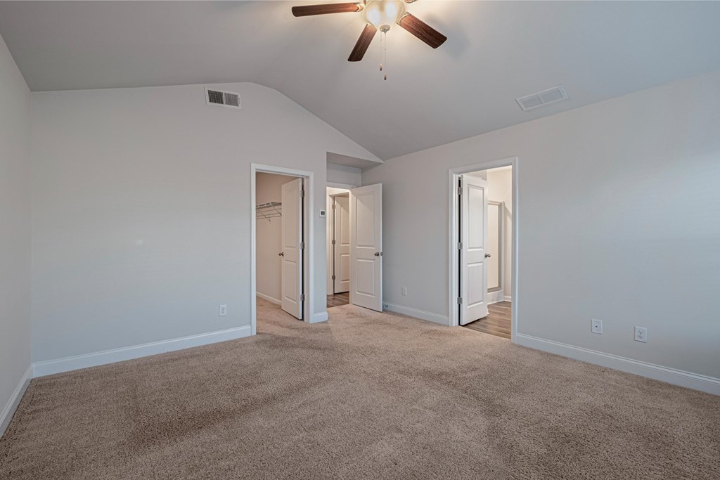 a spacious living room with white walls and a ceiling fan