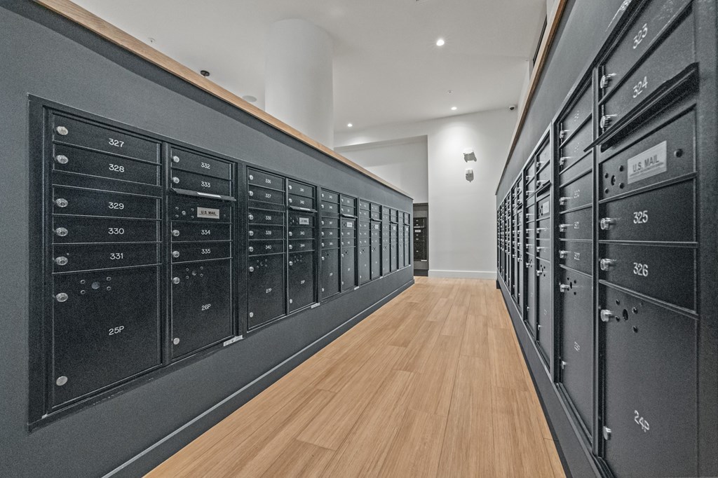 A long hallway with black mailboxes on the wall.