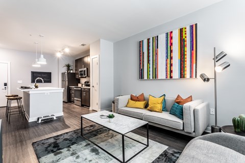 A modern living room with a white sofa and a colorful abstract painting on the wall.