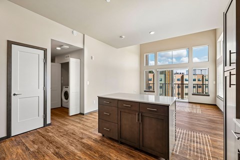 A large, empty room with wooden floors and a view of the city through the windows.