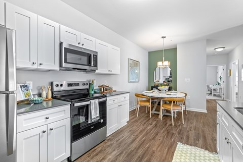 A kitchen with white cabinets and a wooden table.