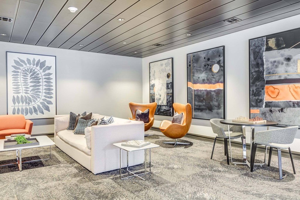 A modern living room with a white sofa, orange chair, and a grey rug.