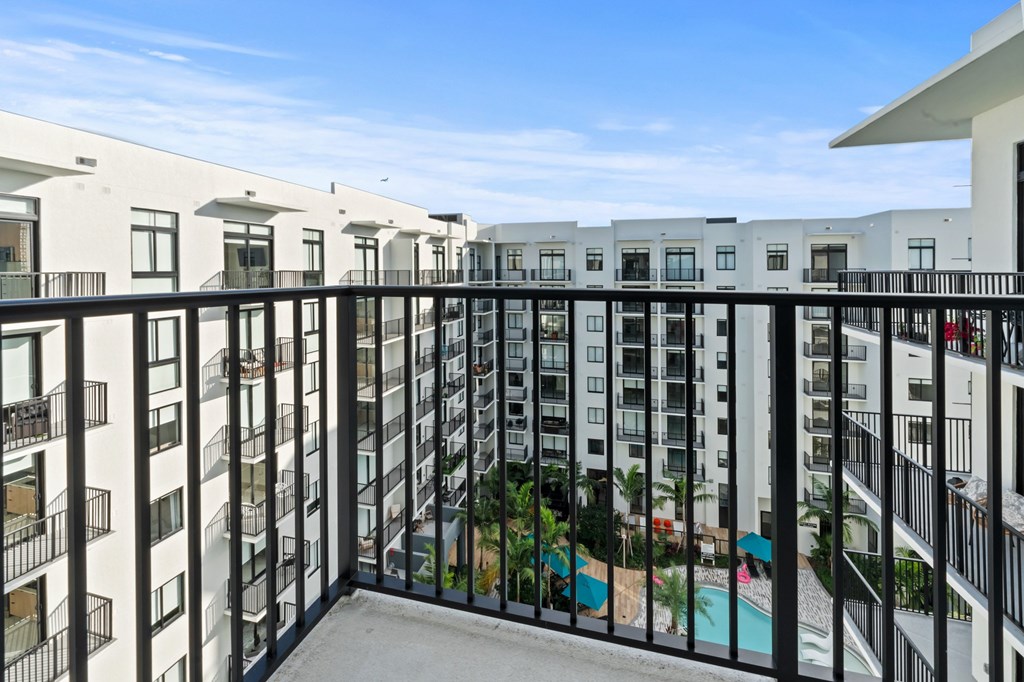 A balcony overlooks a pool and greenery in a residential building.
