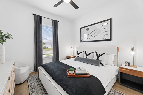 A bedroom with a large bed and a ceiling fan.