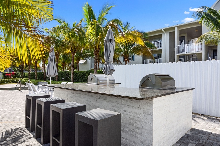 Outdoor kitchen with two grilles, bar seating and umbrellas