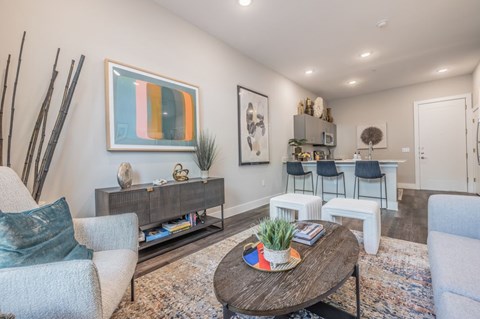 A living room with a grey couch, a wooden coffee table, and a painting on the wall.