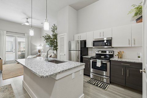 A modern kitchen with a granite countertop and stainless steel appliances.