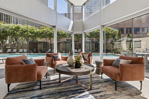 A patio with a table and chairs with a view of a pool and trees.
