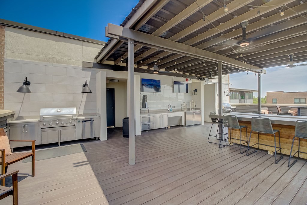 a covered patio with a grill and a bar with stools