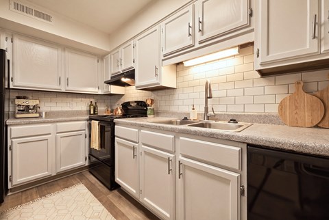 A kitchen with white cabinets and a black oven.