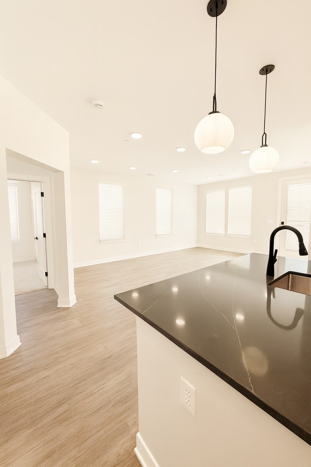 A modern kitchen with a dark countertop and pendant lights.