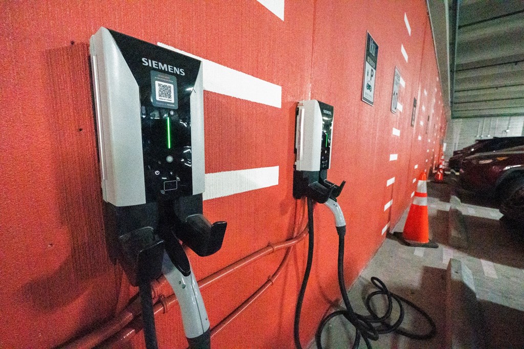 A Siemens electric vehicle charging station is installed on a red wall.