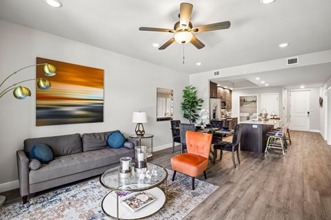 A living room with a grey couch, a coffee table, and a painting on the wall.