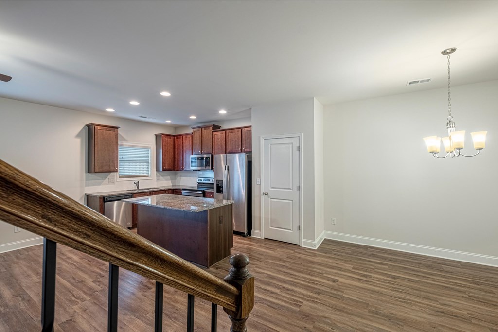 a kitchen with an island and a refrigerator and a staircase