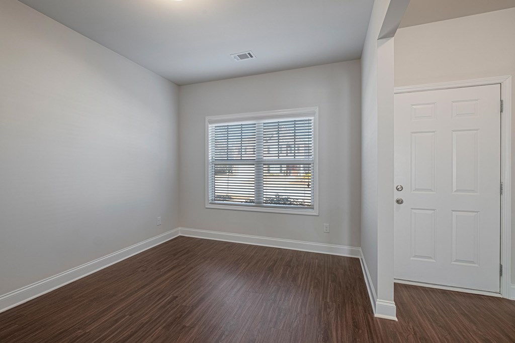 an empty living room with wood floors and a window