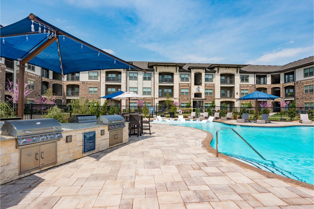 a swimming pool with a bar and barbecue next to an apartment building