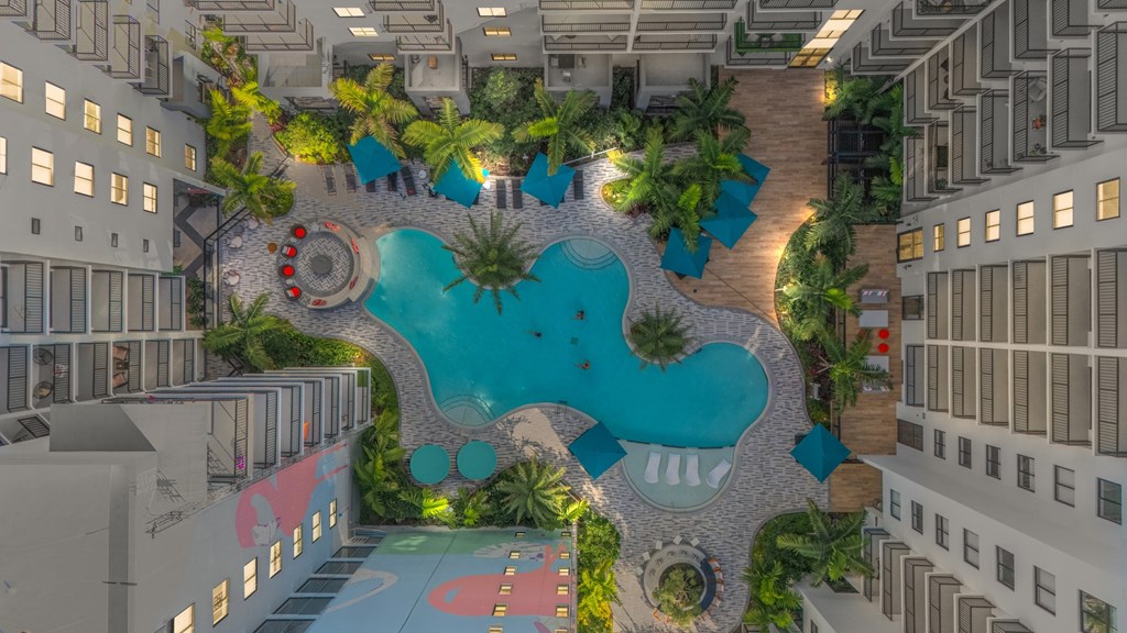 A pool surrounded by palm trees and a winding walkway.